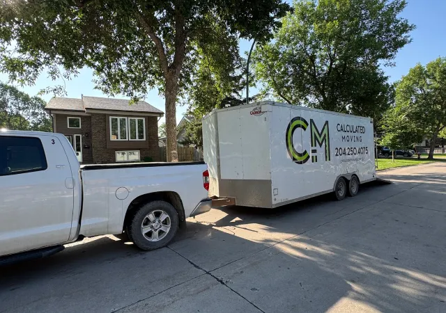 Calculated Moving truck and enclosed trailer parked in front of a Winnipeg residential home for a junk removal and move-out service