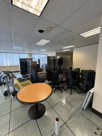 Office chairs and shrink-wrapped furniture staged for an office move by Calculated Moving, commercial movers in Winnipeg